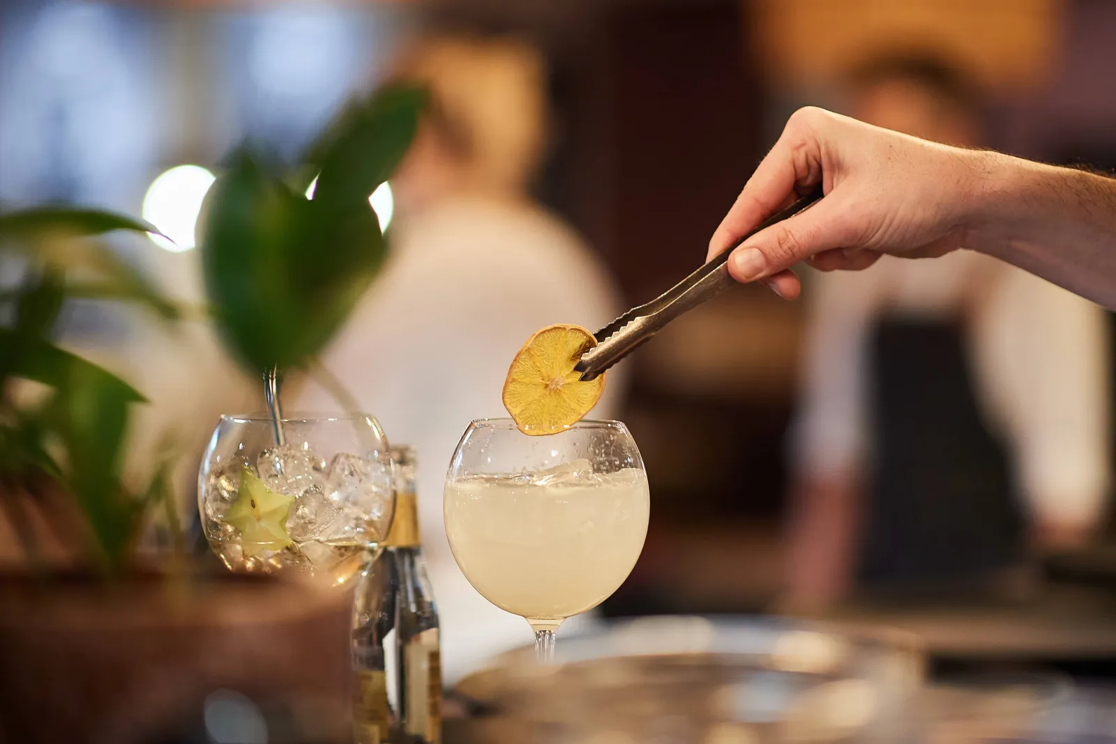 Een barman legt een gedroogd citroenschijfje op een cocktail