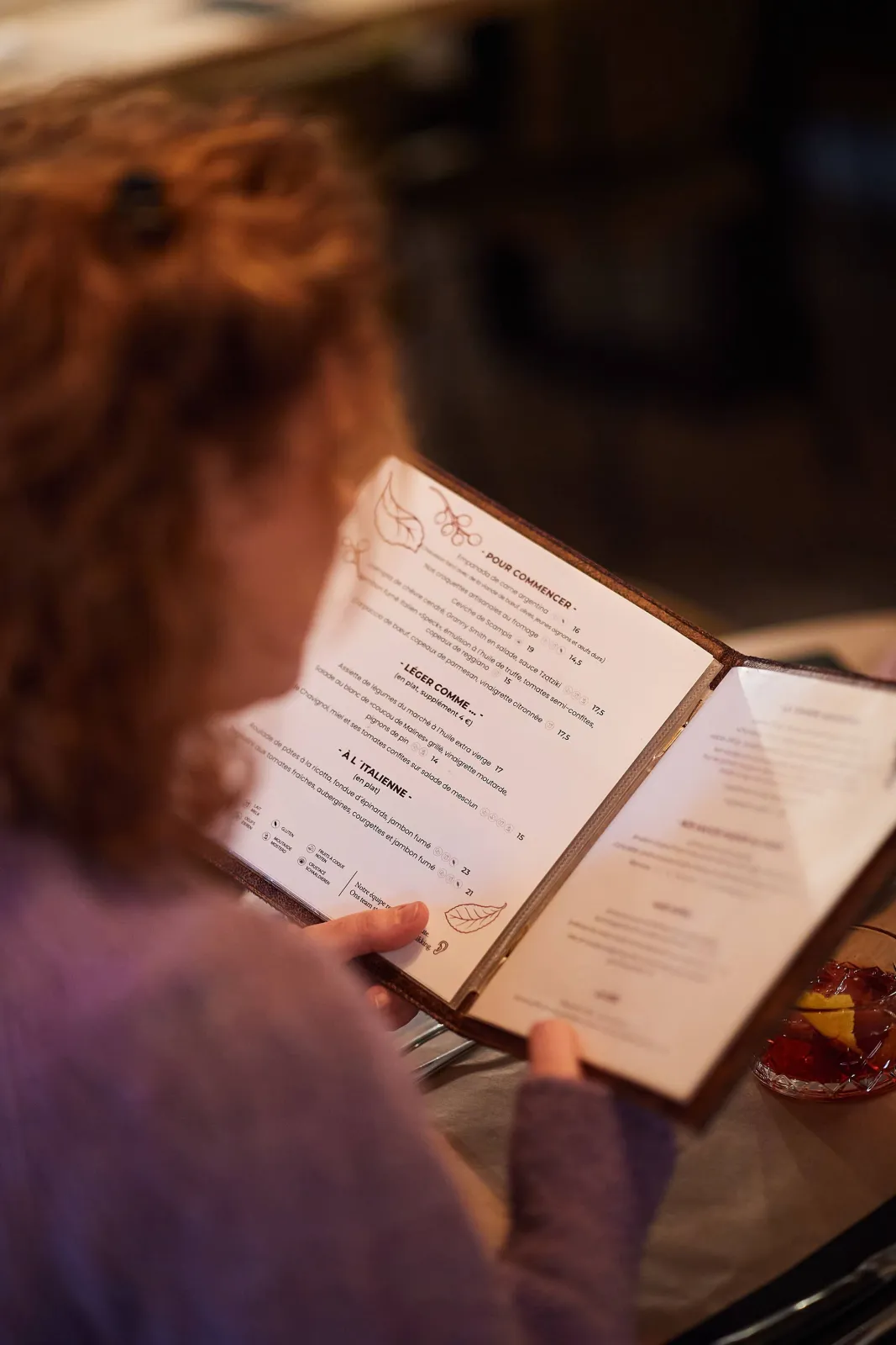Een gaste leest de menukaart aan tafel