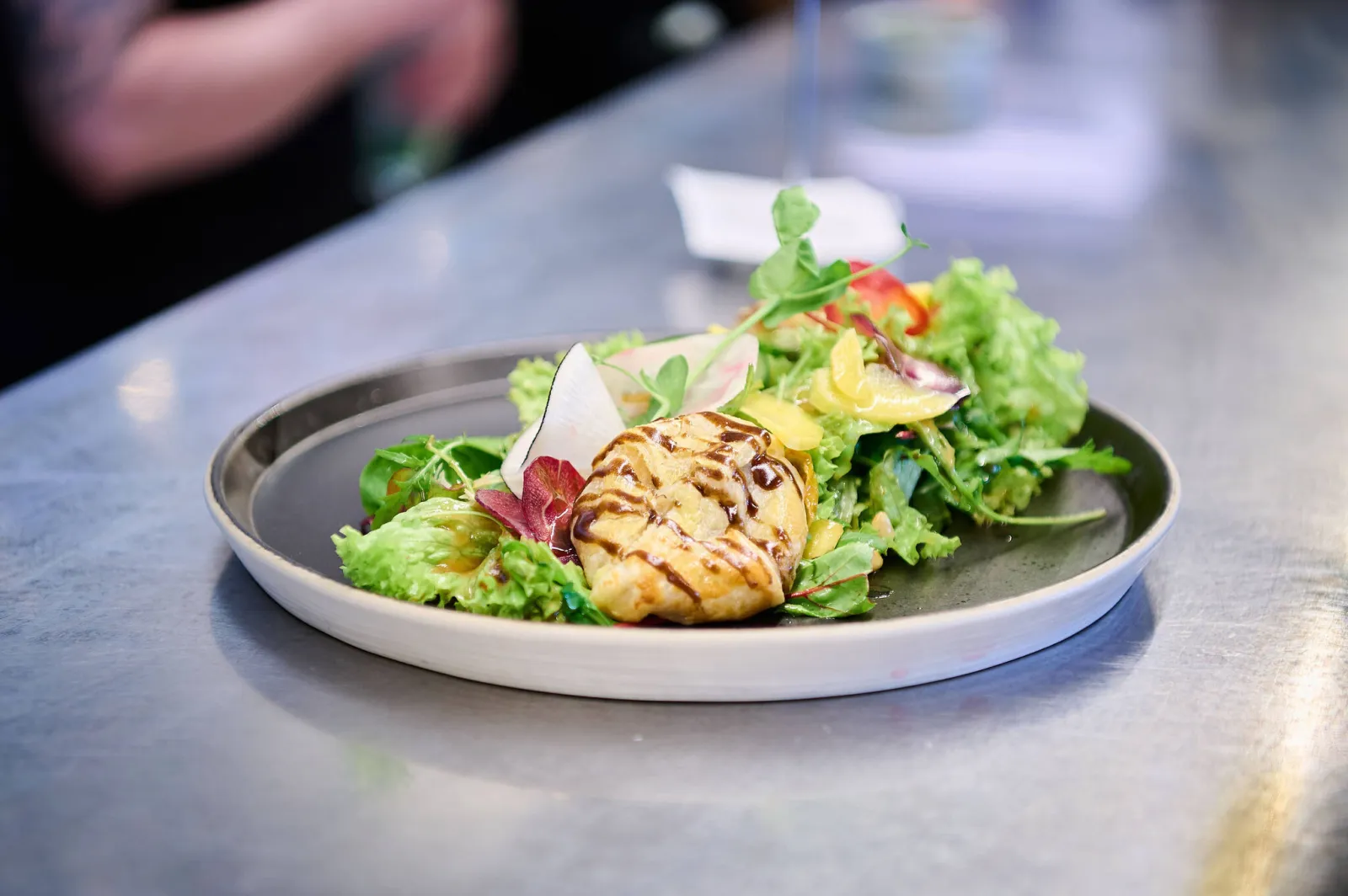 Gemengde groene salade met een warm, gegrild hapje en balsamicosaus