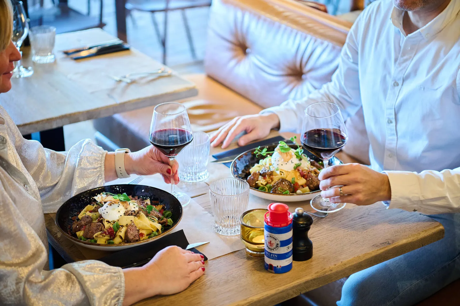 Twee gasten met rode wijn aan tafel bij hun pastaborden