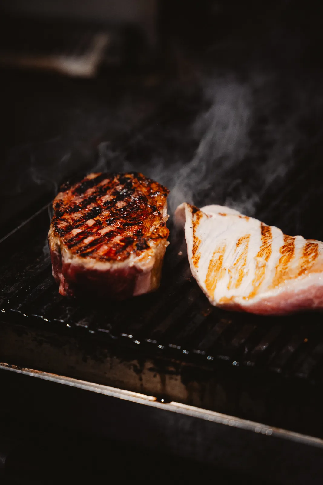 Twee stukken rundvlees met grillstrepen op de rokende grill