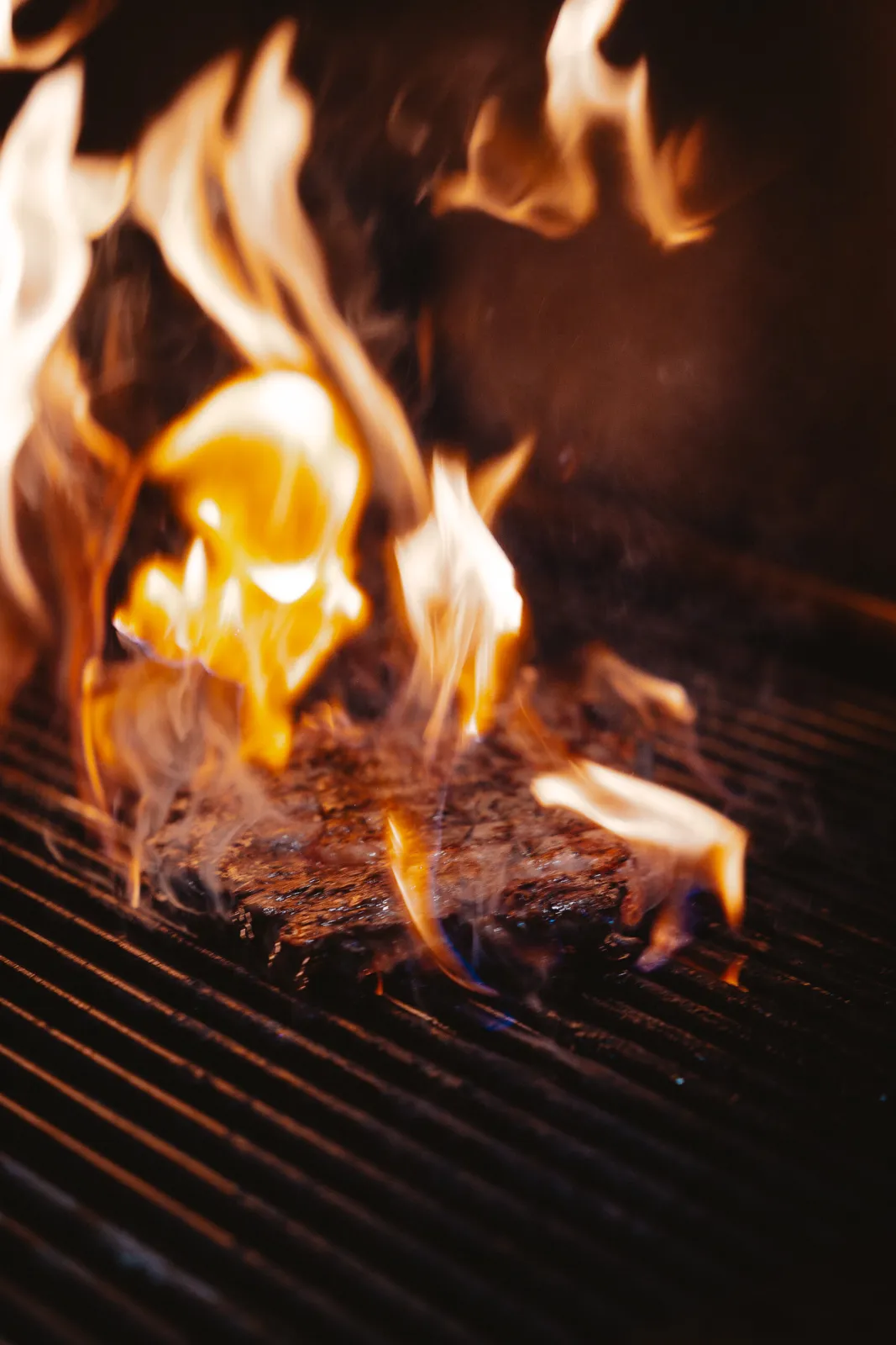 Hoge vlammen slaan op uit de grill in de keuken
