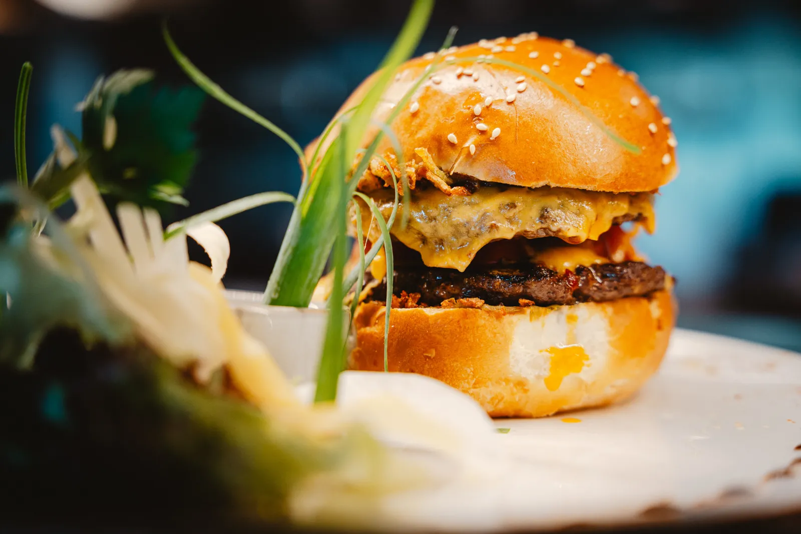 Hamburger met kaas en sesambroodje, met lente-ui als garnering