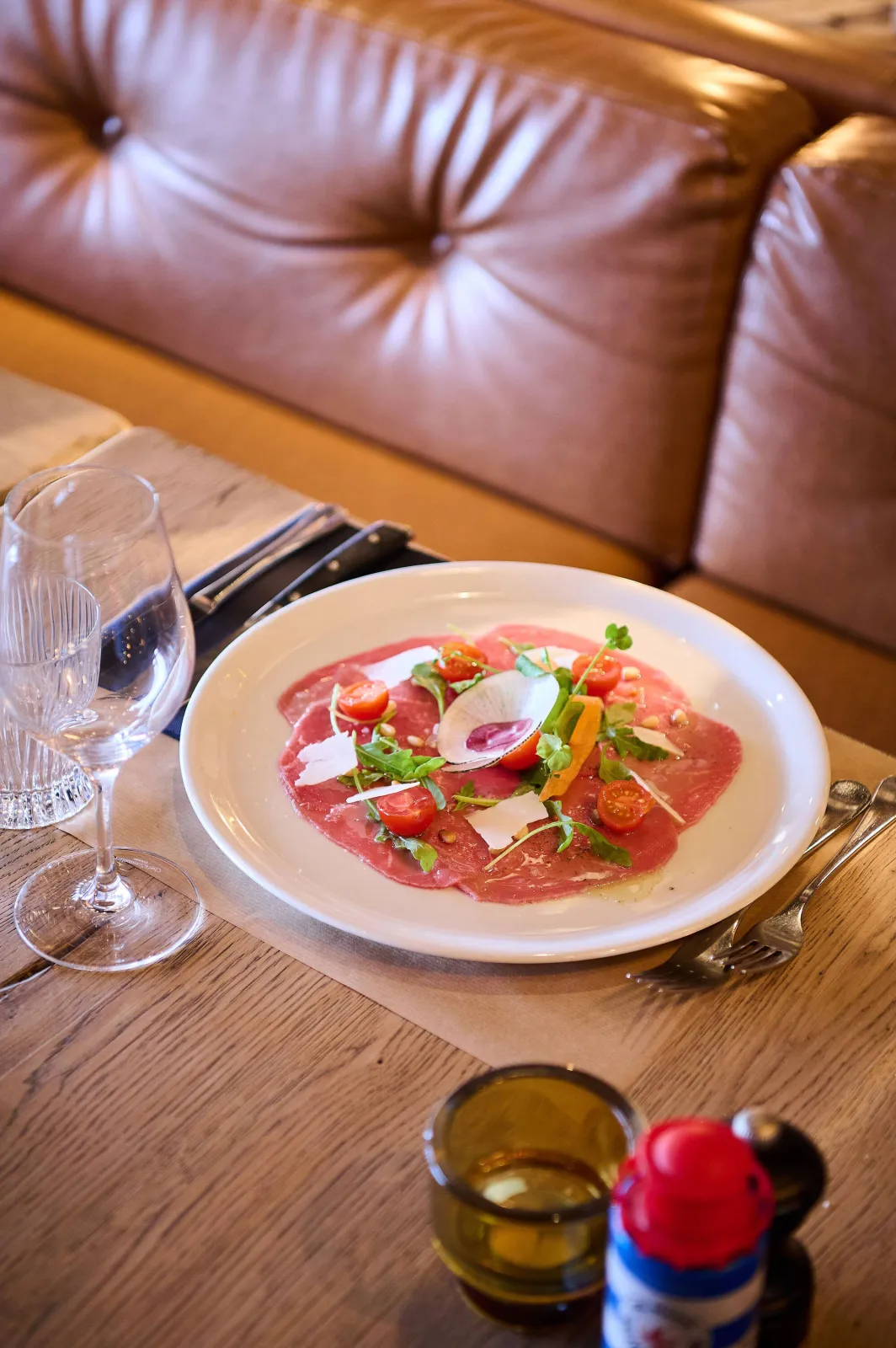 Carpaccio met rucola, kerstomaatjes en Parmezaanse schilfers op een wit bord