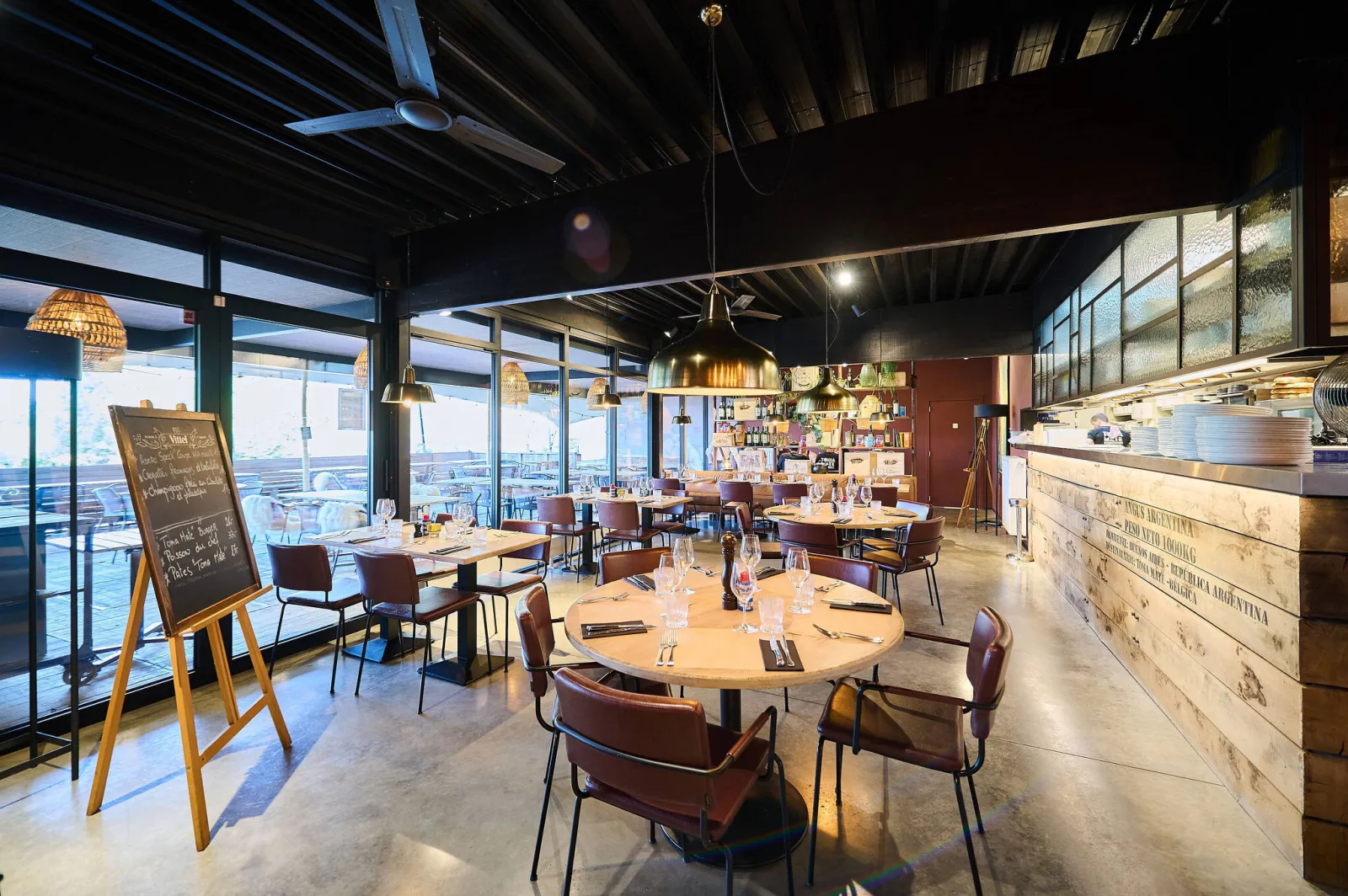 Lichte eetzaal met ronde tafels, krijtbord en grote ramen