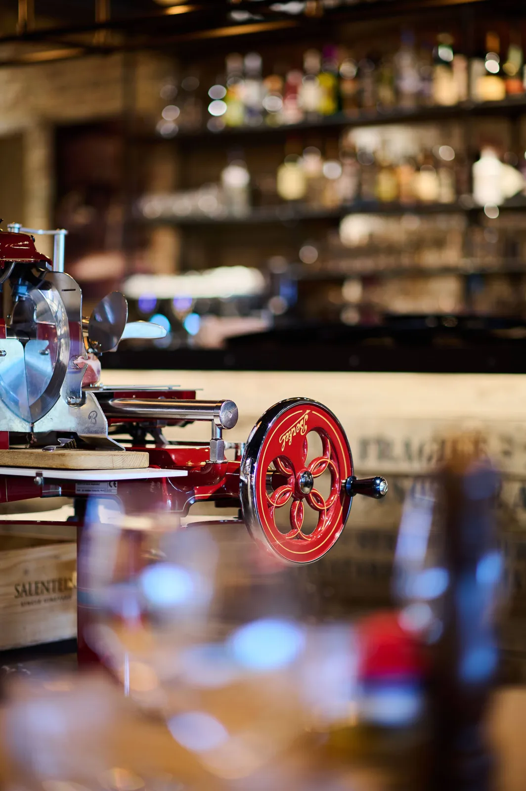 Rode vleessnijmachine voor de bar met flessen op de achtergrond