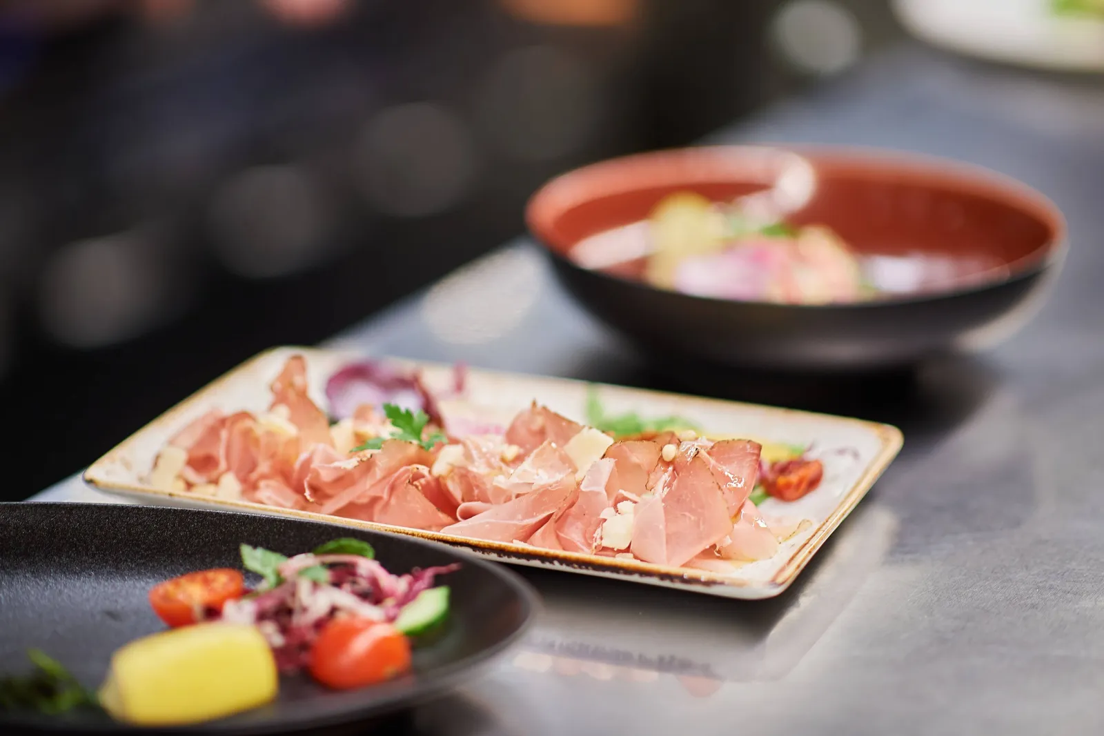 Bord met dun gesneden ham, met andere gerechten op de achtergrond