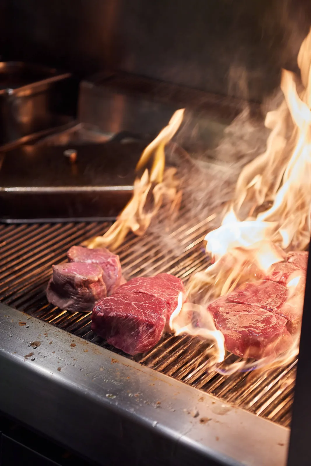 Steaks op de grill tussen hoog oplaaiende vlammen