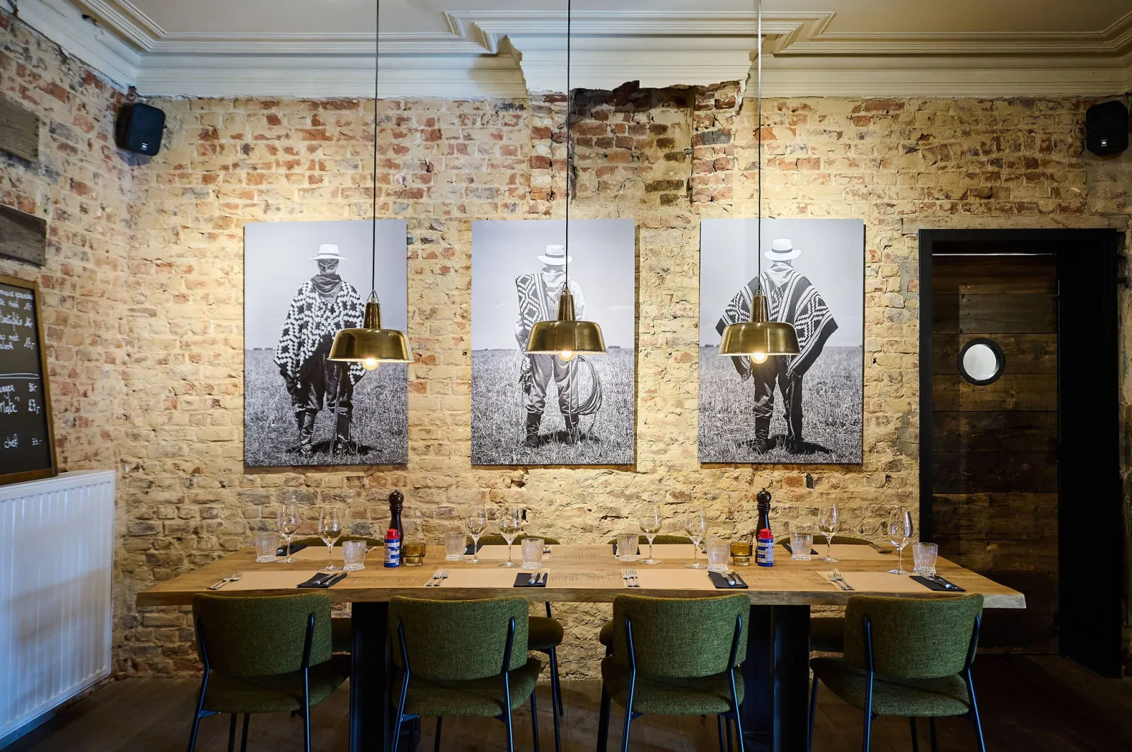Lange tafel voor een bakstenen muur met drie zwart-witfoto's van gaucho's