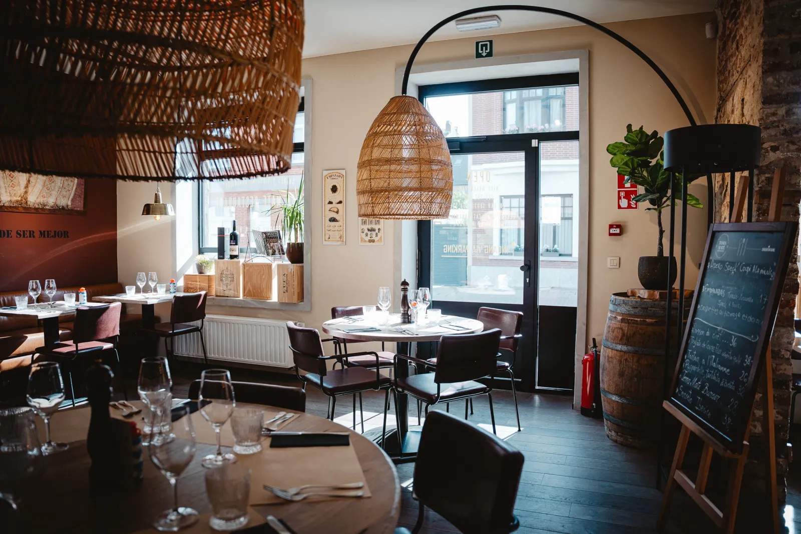 Eetzaal met rotan lampen, een wijnvat en een krijtbord bij de deur