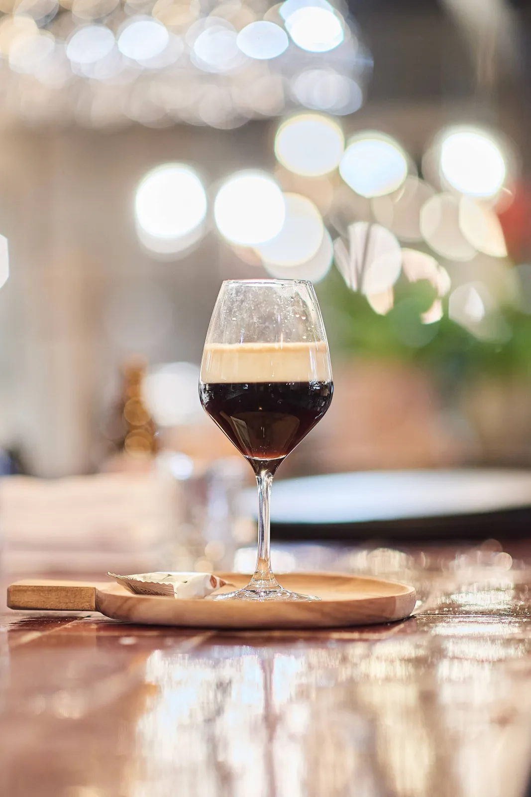 Glas donker bier met schuimkraag op een houten plankje