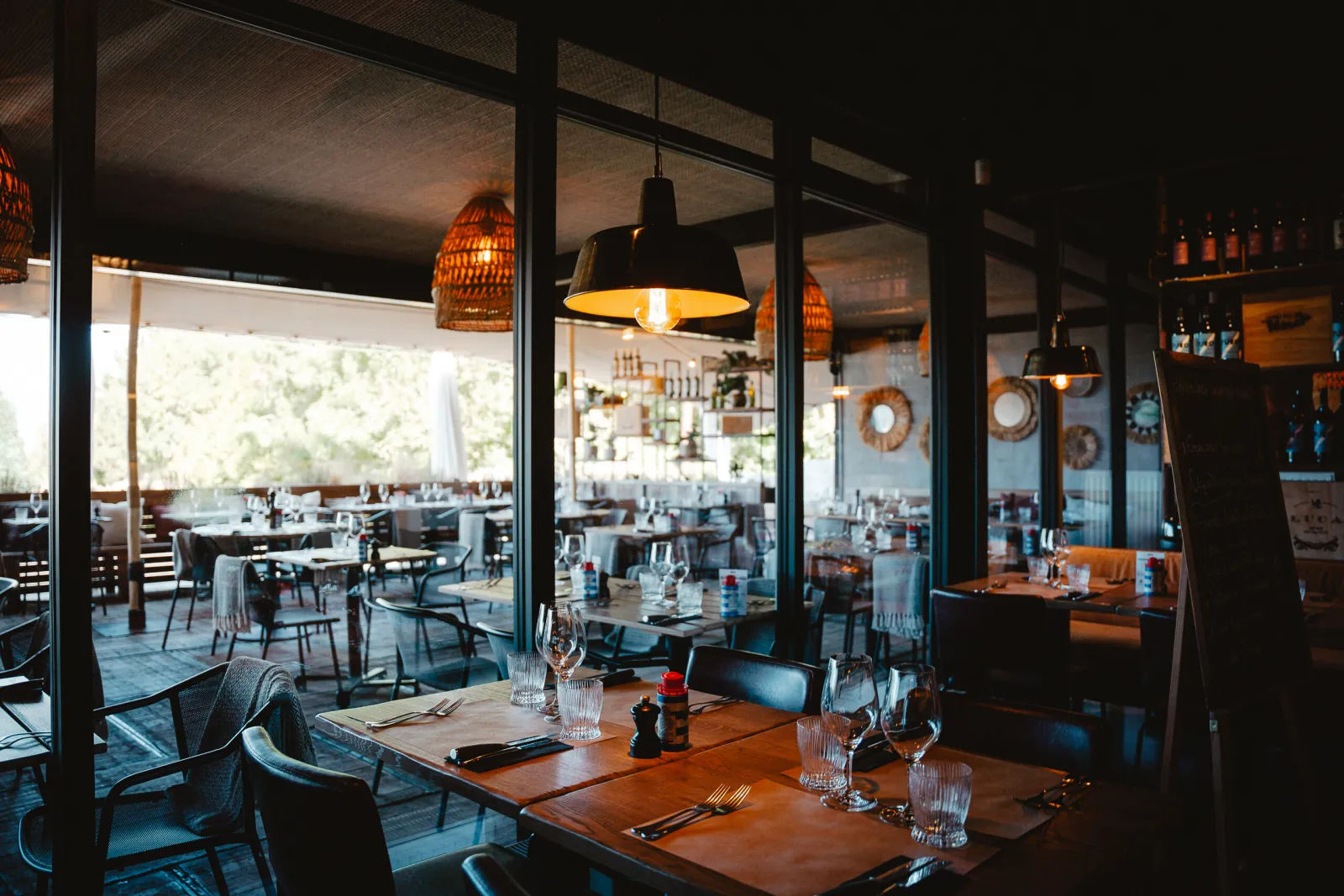 Eetzaal met houten tafels en zicht op het overdekte terras