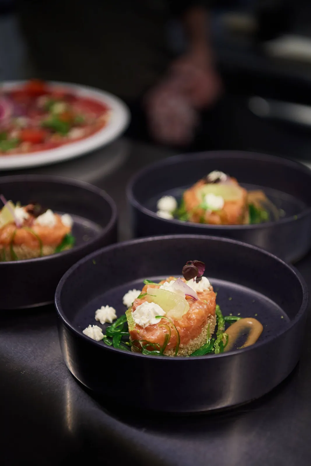 Drie zwarte kommen met een torentje zalm, groenten en verse kaas