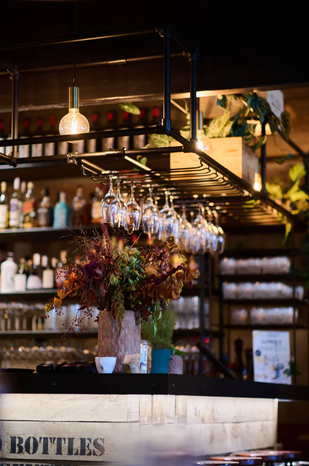 Bar met hangend glazenrek, flessen en een boeket bloemen