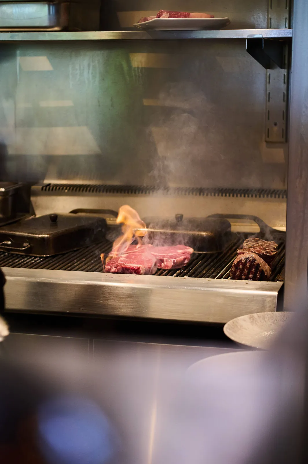 Twee stukken rundvlees op de grill in de keuken, met een vlammetje