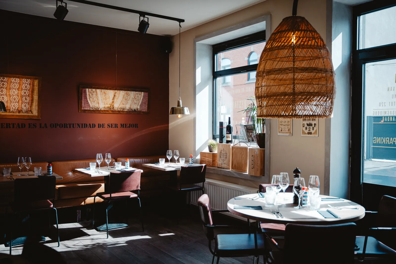 Zonnige eetzaal met rotan lamp, ronde tafel en tekst op de muur